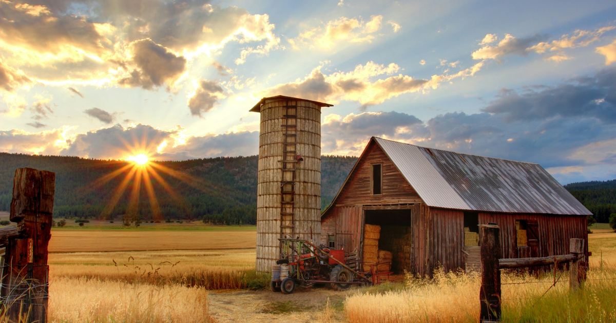 Farmland with a barn and silo at sunset, representing rural land with development potential
