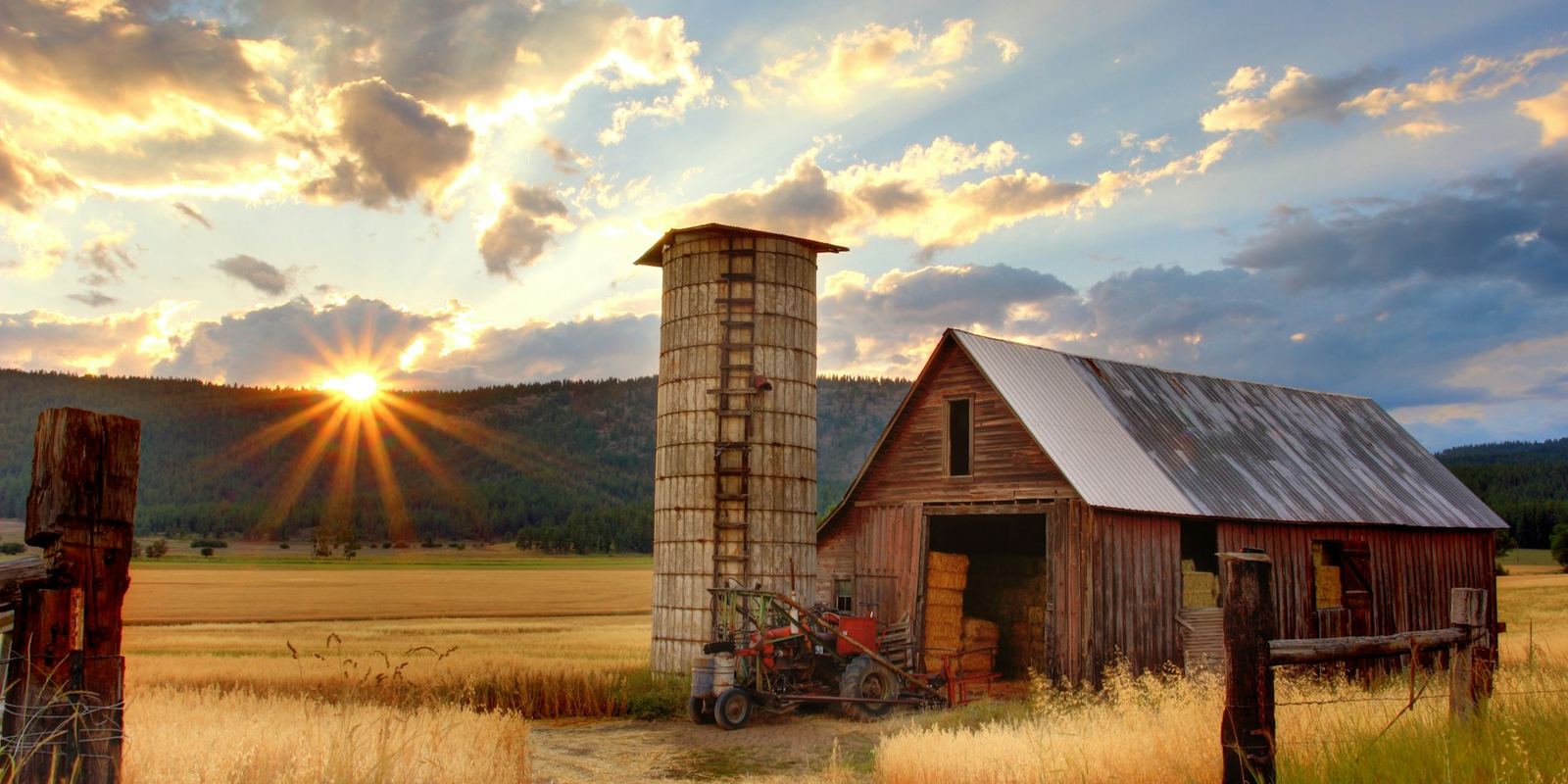 Farmland with a barn and silo at sunset, representing rural land with development potential
